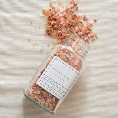 Petite Rose Petal Bath Salt Jar, spilling out on a cream background.