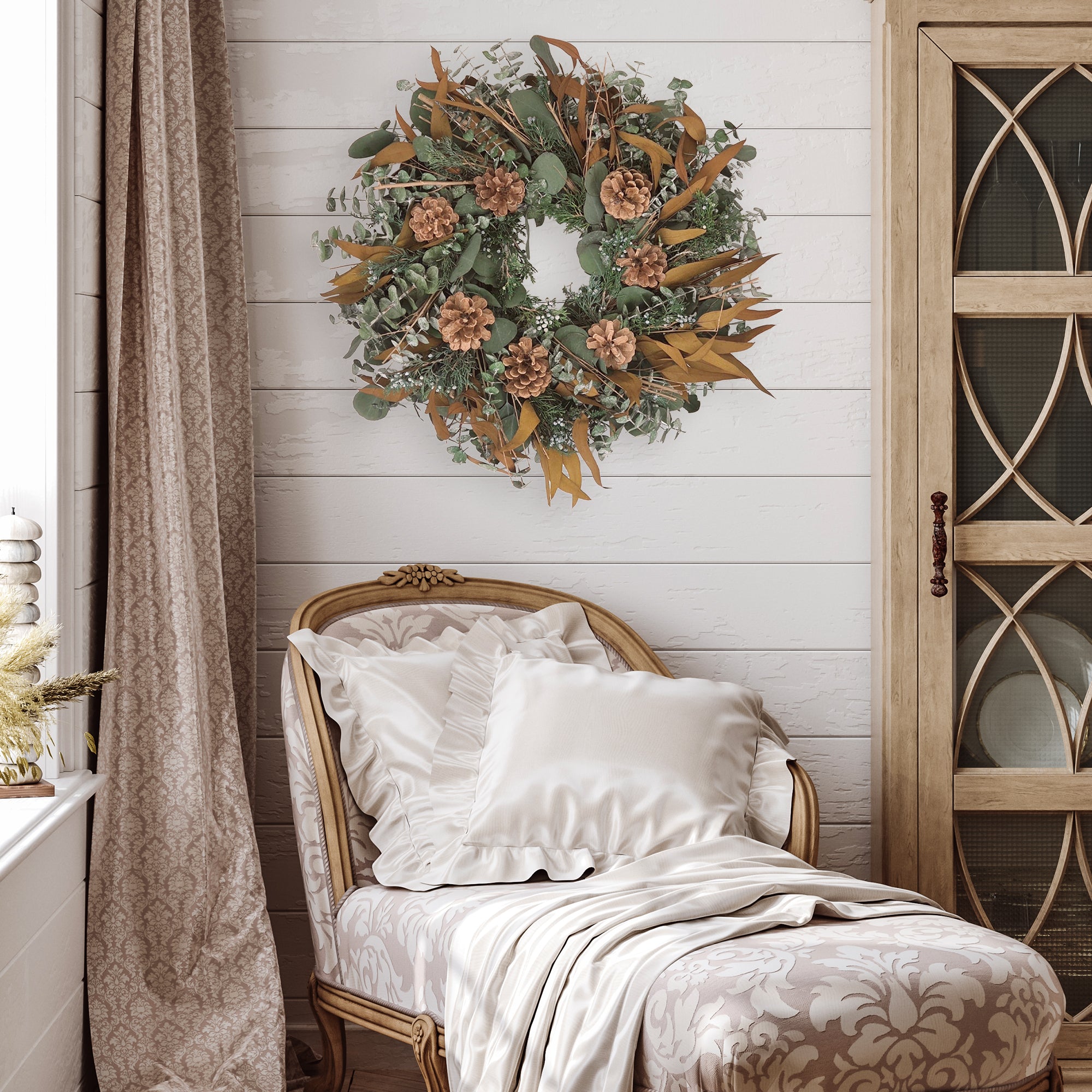 Decorative wreath with greenery, pinecones, and brown leaves in a room setting.