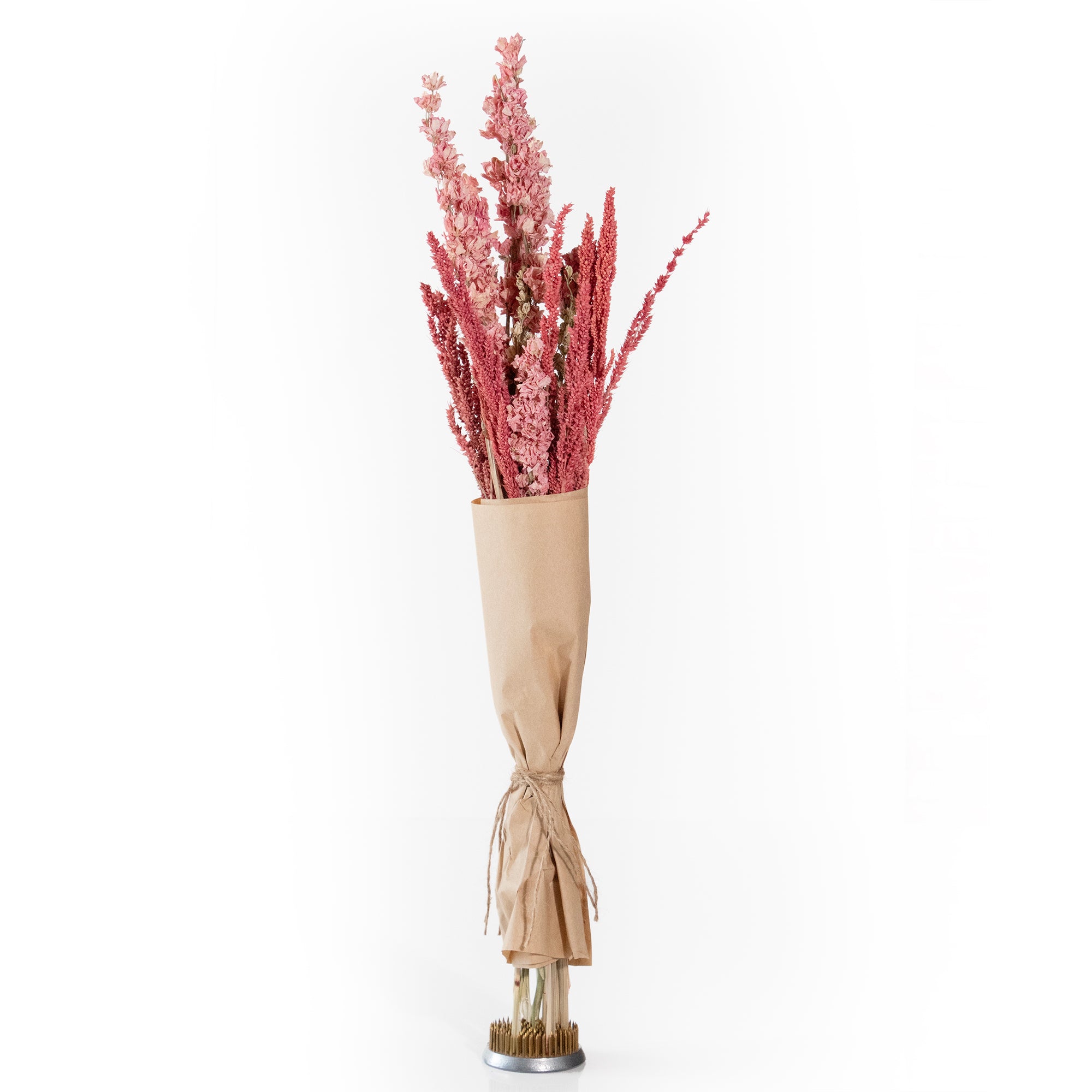 Pink floral bouquet with grains wrapped in brown paper.