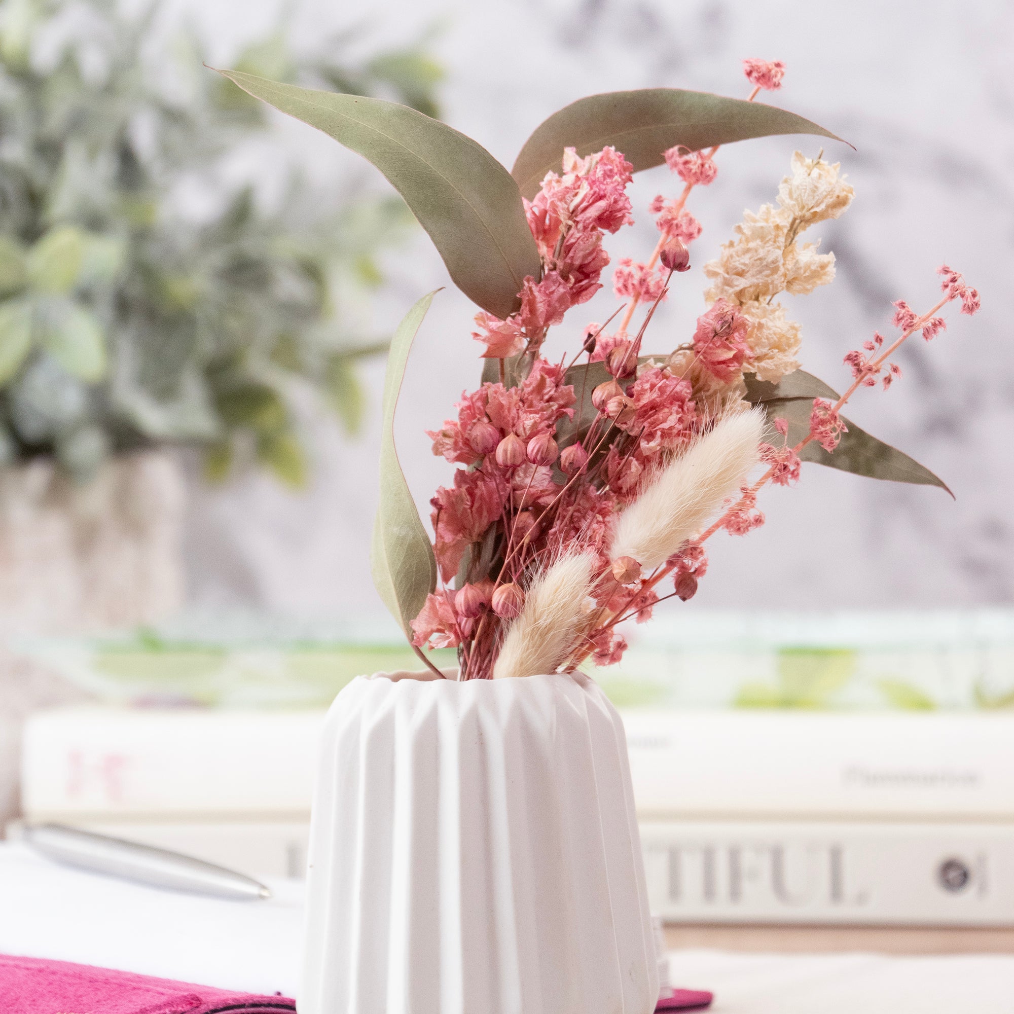 Mini bouquet of pink and white flowers with green leaves and bunny tail stems.