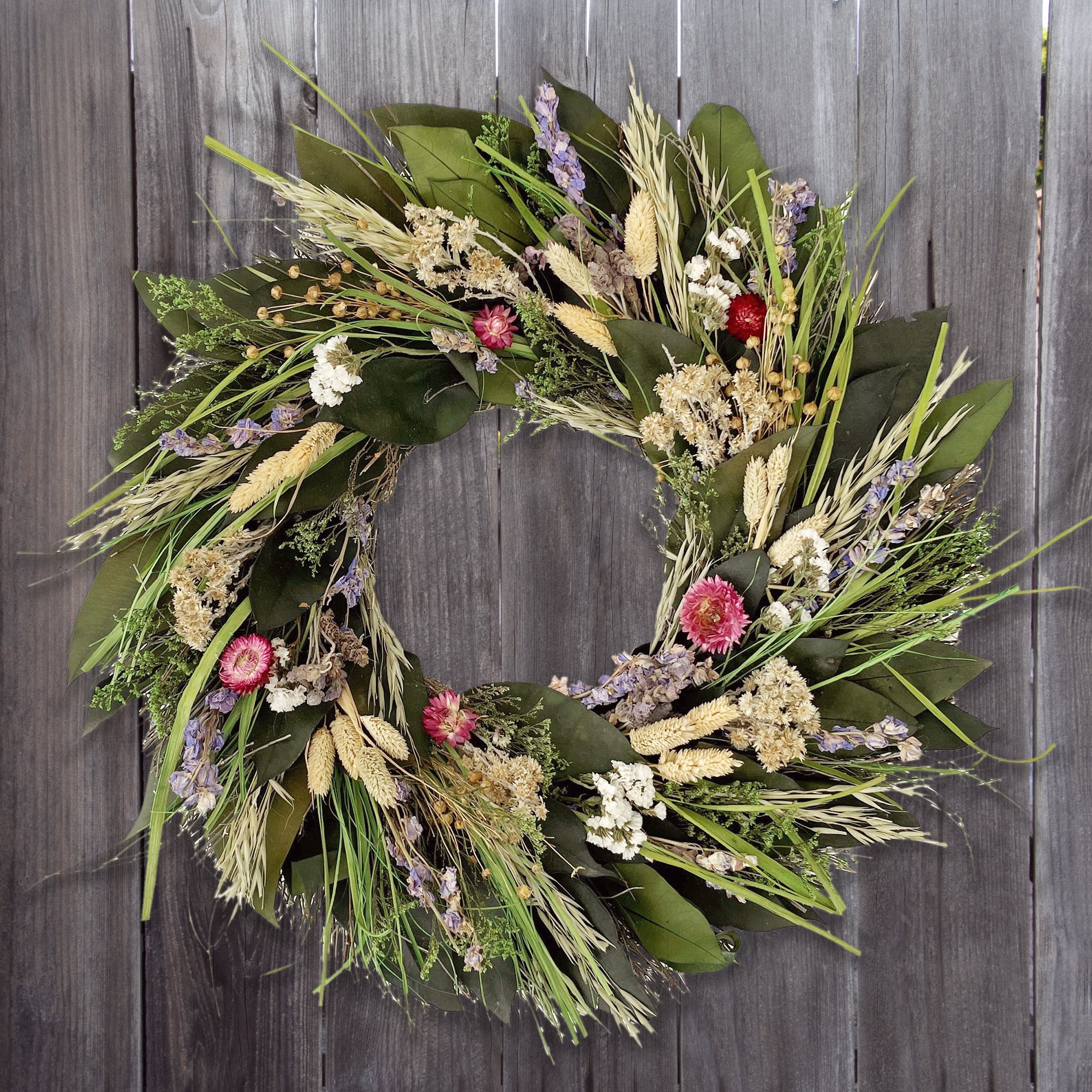 Prairie wreath made from dried flowers in pink, lavender, and white, and natural grains and green leaves.