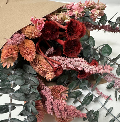 Dried bouquet of pink and red flowers and preserved baby eucalyptus.