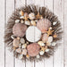 Wreath made from brown starfish, clamshells, and white conch shells on brown twig wreath base.