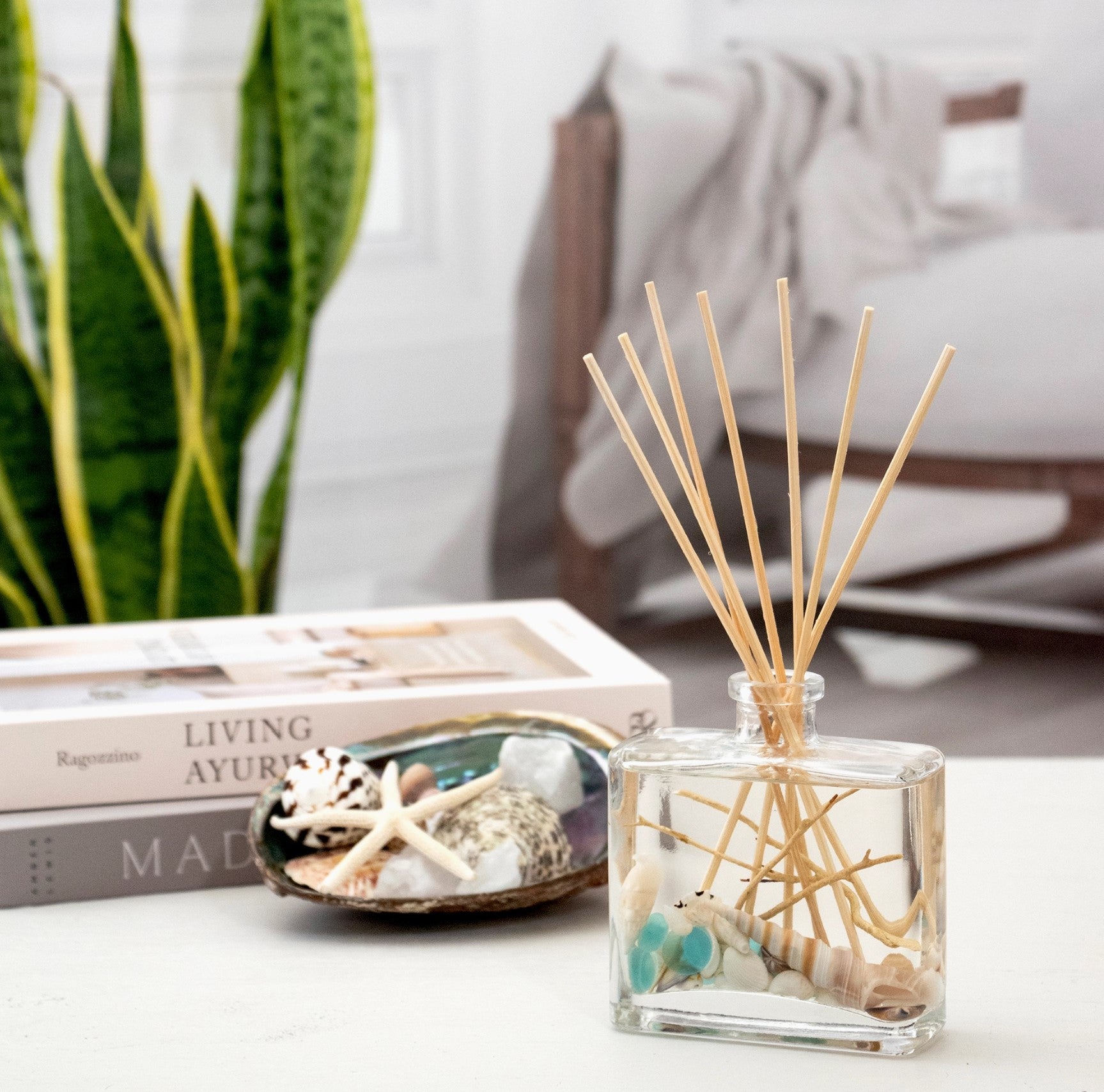 Ocean Plumes fragrance reed diffuser with shells and driftwood inside the bottle.