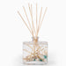 Ocean Plumes fragrance reed diffuser with shells and driftwood inside the bottle.