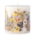 Ivory pillar candle with delicate pressed flowers in yellow and white along with green leaves decorating the outside of the candle.