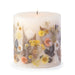 Ivory pillar candle with delicate pressed flowers in yellow and white along with green leaves decorating the outside of the candle.