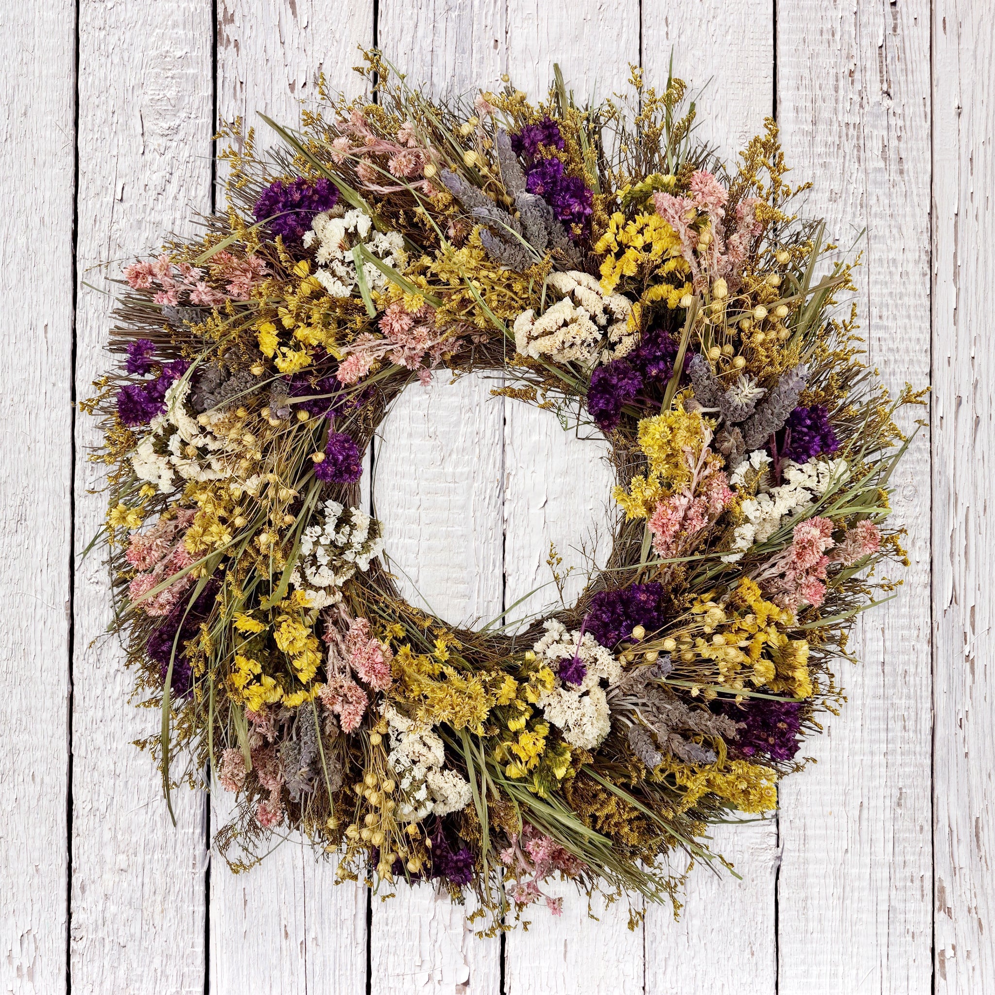 Bright wildflower wreath with yellow, purple, pink, white, and green.