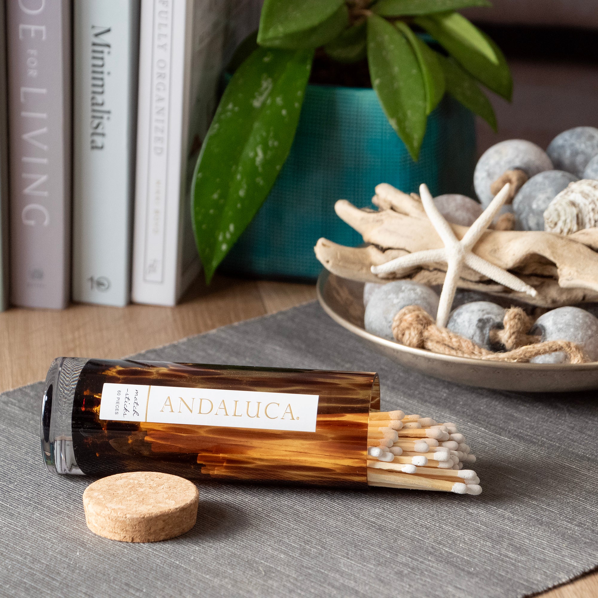 Andalucá incense bottle with matches on a table with books and decorative items in the background