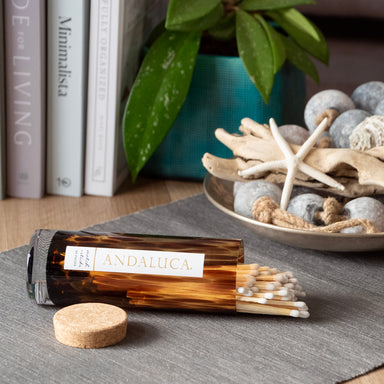 Andalucá incense bottle with matches on a table with books and decorative items in the background