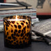 A lit Tortoise Glass candle, set on a dark tabletop next to books.