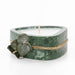Candle in a green marble container with twine and leaves on a white background