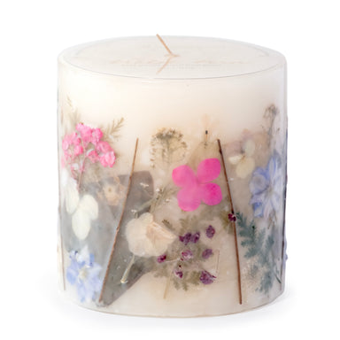 Ivory pillar candle with delicate pressed pink and purple flowers and green leaves decorating the outside of the candle.