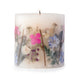 Ivory pillar candle with delicate pressed pink and purple flowers and green leaves decorating the outside of the candle.