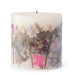 Ivory pillar candle with delicate pressed pink and purple flowers and green leaves decorating the outside of the candle.