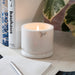 Lit white marble candle cup. Product shot, on a table.
