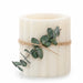 White candle with eucalyptus branch tied with twine on a white background