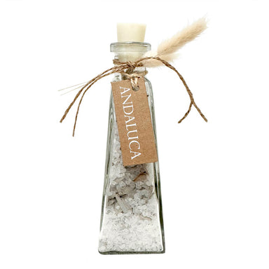 Clear glass bottle with bath salt and white sage inside.
