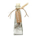 Clear glass bottle with bath salt and white sage inside.