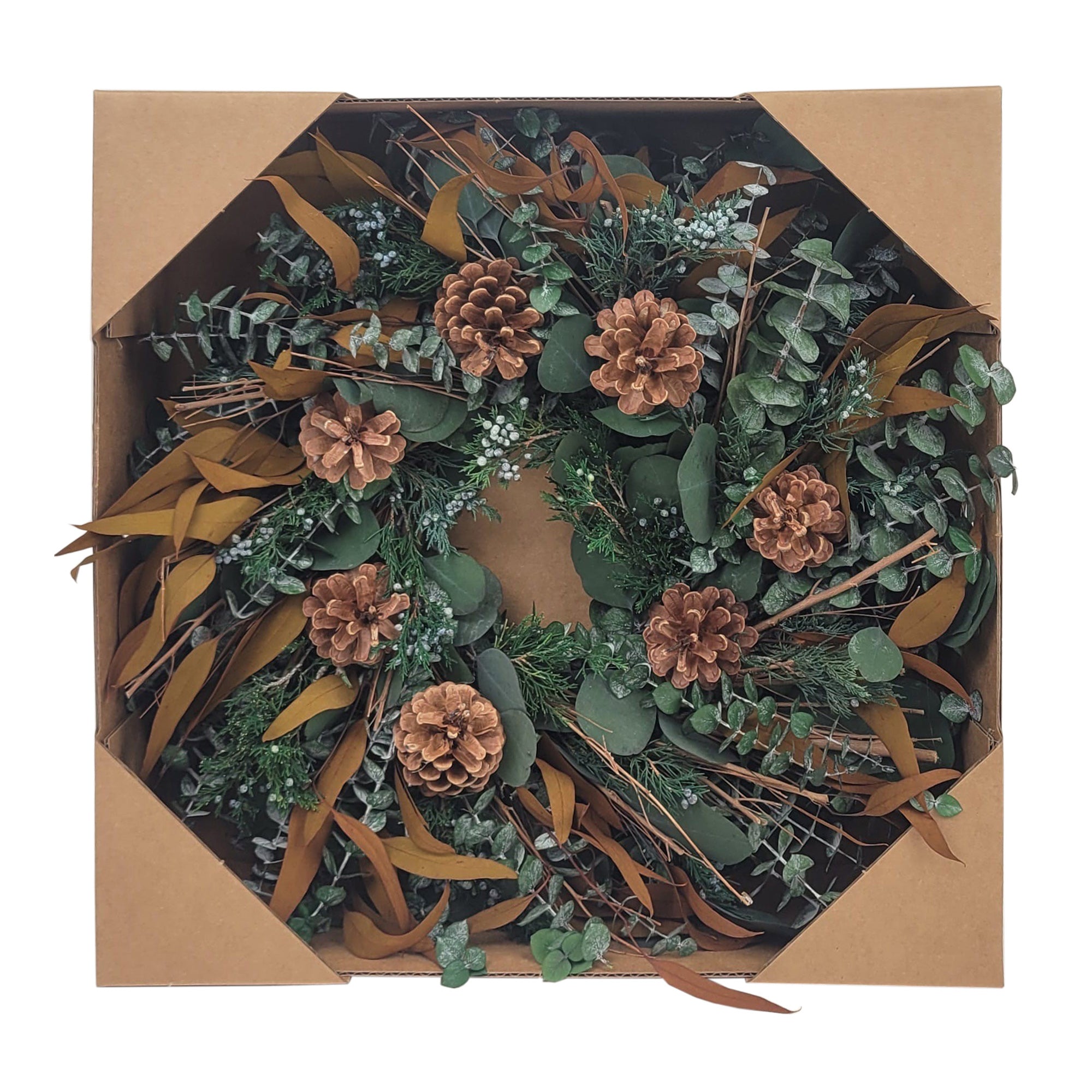 Decorative wreath with greenery and pinecones in a cardboard box