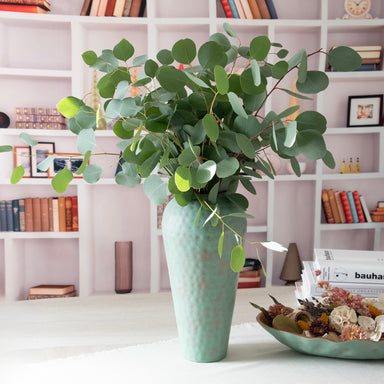 metal vase in room setting with fresh eucalyptus.