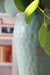 close up, metal vase in room setting with fresh eucalyptus.